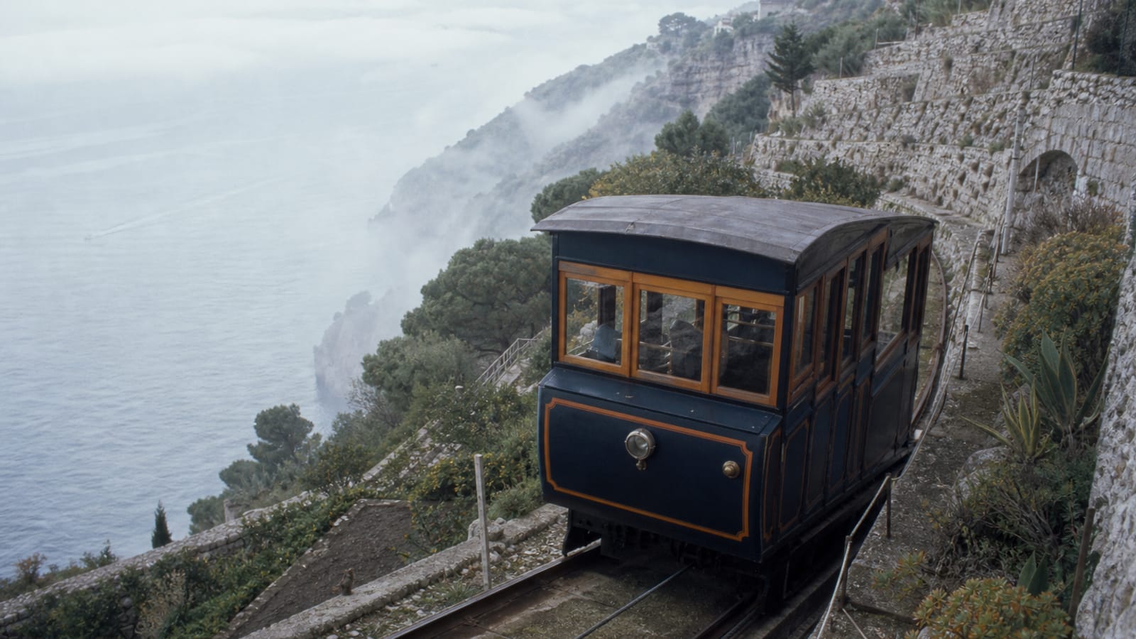 A funicular car climbing the terraced cliffs of Skalda above the sea.
