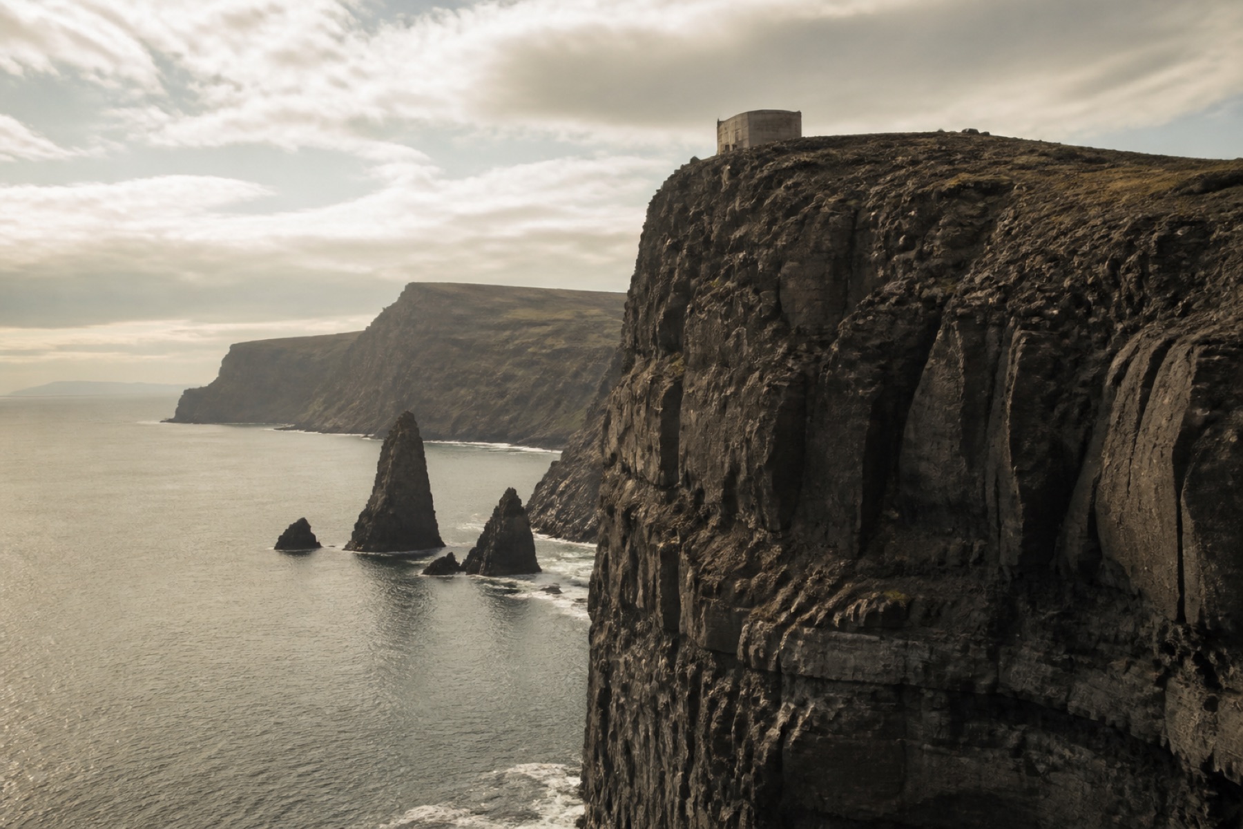 Basalt cliffs at North Head, with a pale metro ventilation house on the headland.